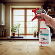 Hand holding a spray bottle labeled 'samba' in a kitchen setting